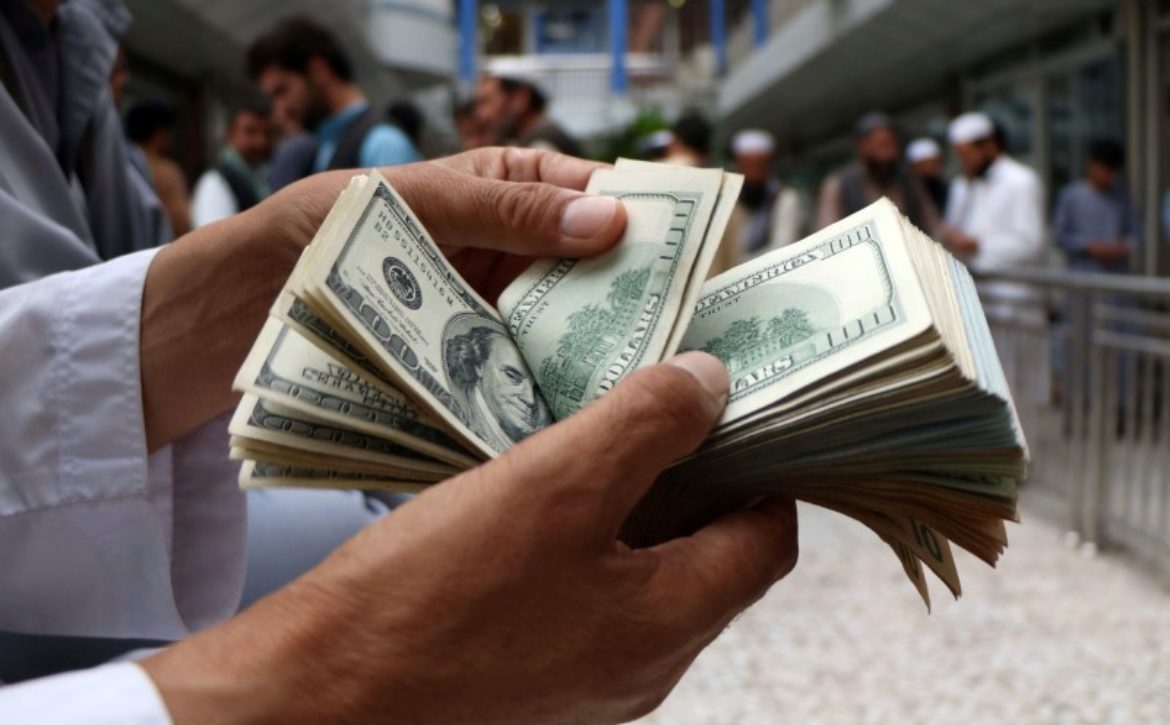 A money changer counts U.S. dollar banknotes at money change market in Herat province