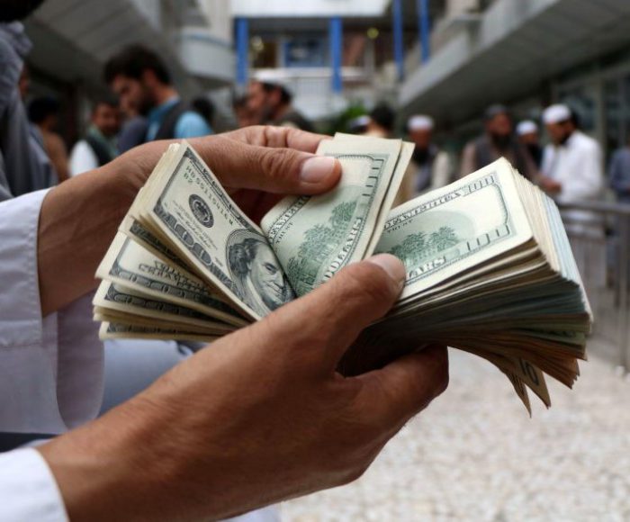 A money changer counts U.S. dollar banknotes at money change market in Herat province